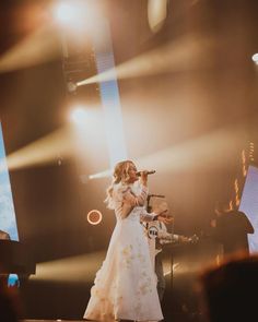 a woman standing on top of a stage holding a microphone in front of a crowd