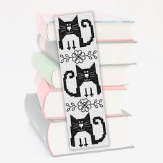 a cross stitch bookmark with black and white cats sitting on top of each other