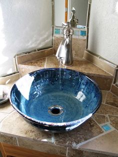 a blue bowl sink sitting on top of a bathroom counter next to a faucet