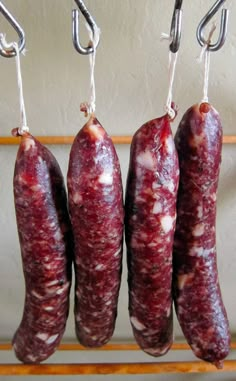 four sausages hanging from hooks on a rack