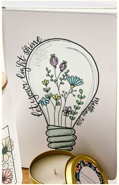 a light bulb with flowers in it sitting on top of a table next to a candle