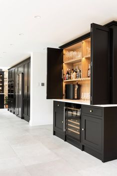 an empty kitchen with black cabinets and white counter tops is pictured in this image, there are wine glasses on the cabinet doors