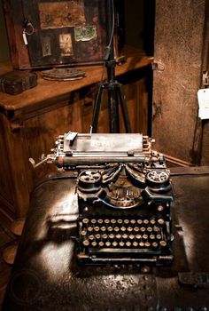 an old fashioned typewriter sitting on top of a table next to a wooden desk