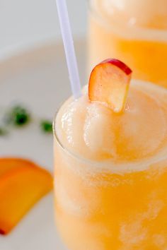 two glasses filled with orange juice and garnished with peach slices on a white plate