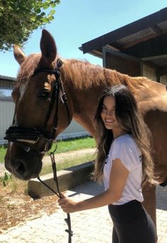 a woman standing next to a brown horse