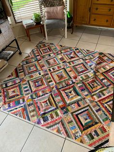 a large multicolored patchwork rug on the floor in a living room next to a chair