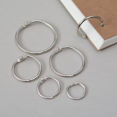 four pairs of silver hoop earrings next to an open book