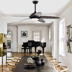 a dining room table with chairs and a black piano in the background, along with a ceiling fan