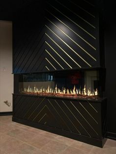 a modern fireplace in a black room with gold lines on the wall and flooring