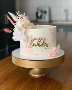 a white and pink birthday cake sitting on top of a wooden table