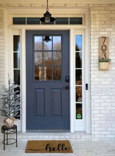 a blue front door with the word hello written on it and a small christmas tree