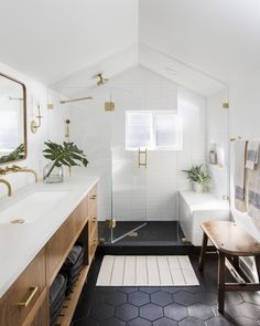 a bathroom with white walls and black flooring has a wooden bench in front of the shower