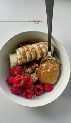 a bowl filled with bananas, raspberries and oatmeal next to a spoon