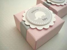 two pink and gray gift boxes with baby's name tags on the top one