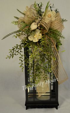 a vase filled with flowers and greenery on top of a table