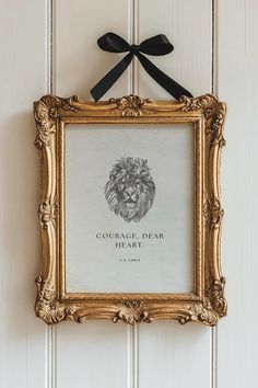 an ornate gold frame with a black ribbon hanging on the wall above it is a portrait of a lion