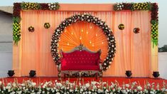 a red couch sitting in front of an orange stage with white flowers and greenery