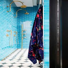 a blue tiled bathroom with an open shower stall and black door in the corner, next to a patterned tile floor