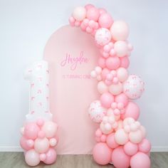 balloon arch with pink and white balloons in front of it for an 1st birthday party