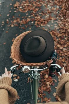 a person riding a bike with a hat on the back of it's basket