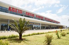 an airport terminal with palm trees in the foreground and people walking around outside it