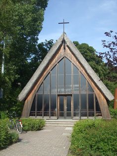 an old church with a bicycle parked in front of it and trees around the building