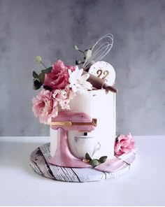 a white cake with pink flowers on top and a whisk in the middle