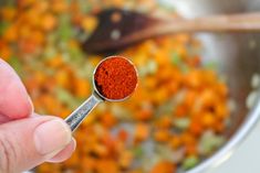 a person holding a spoon with some red stuff in it