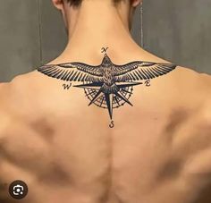 the back of a man's neck with a bird and compass tattoo on it