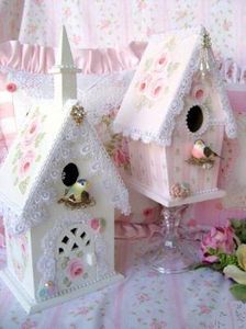 two white birdhouses sitting on top of a table covered in pink and white flowers