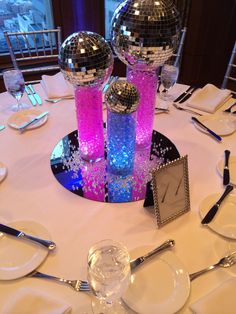 disco ball centerpieces on a round table with silverware and napkins in front of them