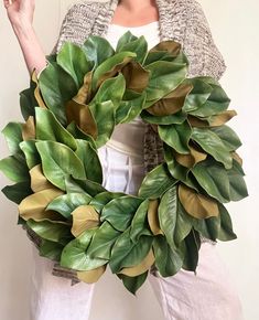 a woman holding a green wreath with leaves