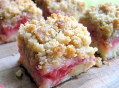 several pieces of dessert sitting on top of a wooden cutting board with crumb toppings