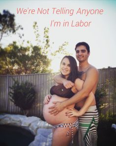 a man and woman standing next to each other in front of a fence with the words we're not telling anyone i'm'm in labor