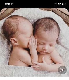 two babies are cuddling together on a blanket