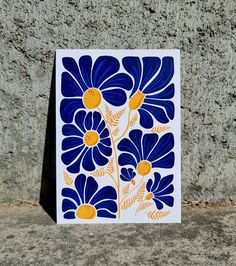 a blue and yellow tile with daisies on the outside, against a stone wall