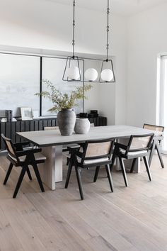 a dining room table with chairs and vases on it