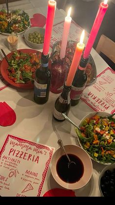 a table topped with lots of food and lit candles on top of it's plates