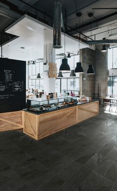 a restaurant with lots of tables and chairs in front of the counter, along with lights hanging from the ceiling