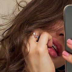 a woman is holding up her cell phone to take a photo with her nose ring