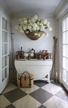 a basket filled with white flowers sitting on top of a table next to an open door