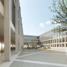 an empty courtyard in front of a large building with many windows and people walking around