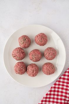 a white plate topped with meatballs next to a red and white checkered napkin