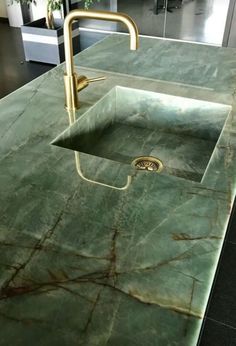 a green marble counter top with a sink and faucet in the middle,