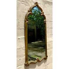 an ornate gold mirror hanging on the side of a wall next to a brick building