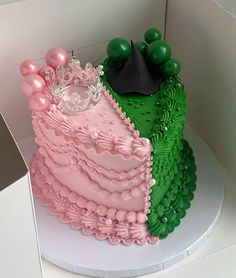 a pink and green cake sitting on top of a white table next to a black hat