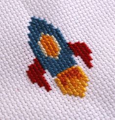 a close up of a cross stitch pattern with a rocket ship design on it's side