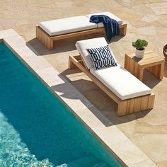 an outdoor pool with chaise lounges next to it