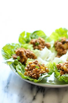 lettuce wraps filled with meat and vegetables on a marble countertop, ready to be eaten