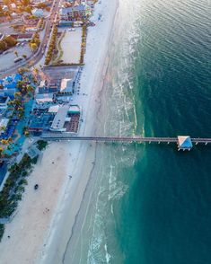 an aerial view of the ocean and beach with a pier in the foreground, surrounded by buildings